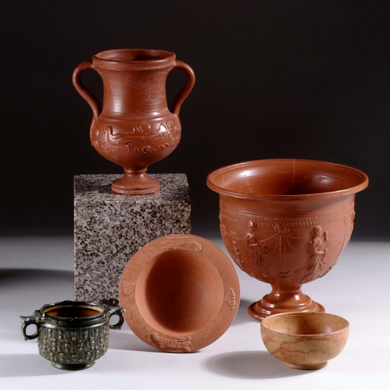 Group of Objects  Pottery: Lead-Glazed ware skyphos; ring-handled, with inturned thickened rim, tall broad body and ring foot; moulded decoration on exterior; overlapping scales of pendant arcs enclosing a disc between two rosettes; on exterior, mid-green glaze, on interior, honey-brown. Pottery: Arretine ware crater with representations of the Seasons. The foot is restored; reconstructed from numerous fragments. Pottery: African Red Slip ware bowl with appliqué decoration of oak sprays and hunting dogs with jewelled or studded collars. 1981 0218 45 - no MERLIN record Pottery: cup of marbled Samian ware, stamped by the potter Castus.  © The Trustees of the British Museum