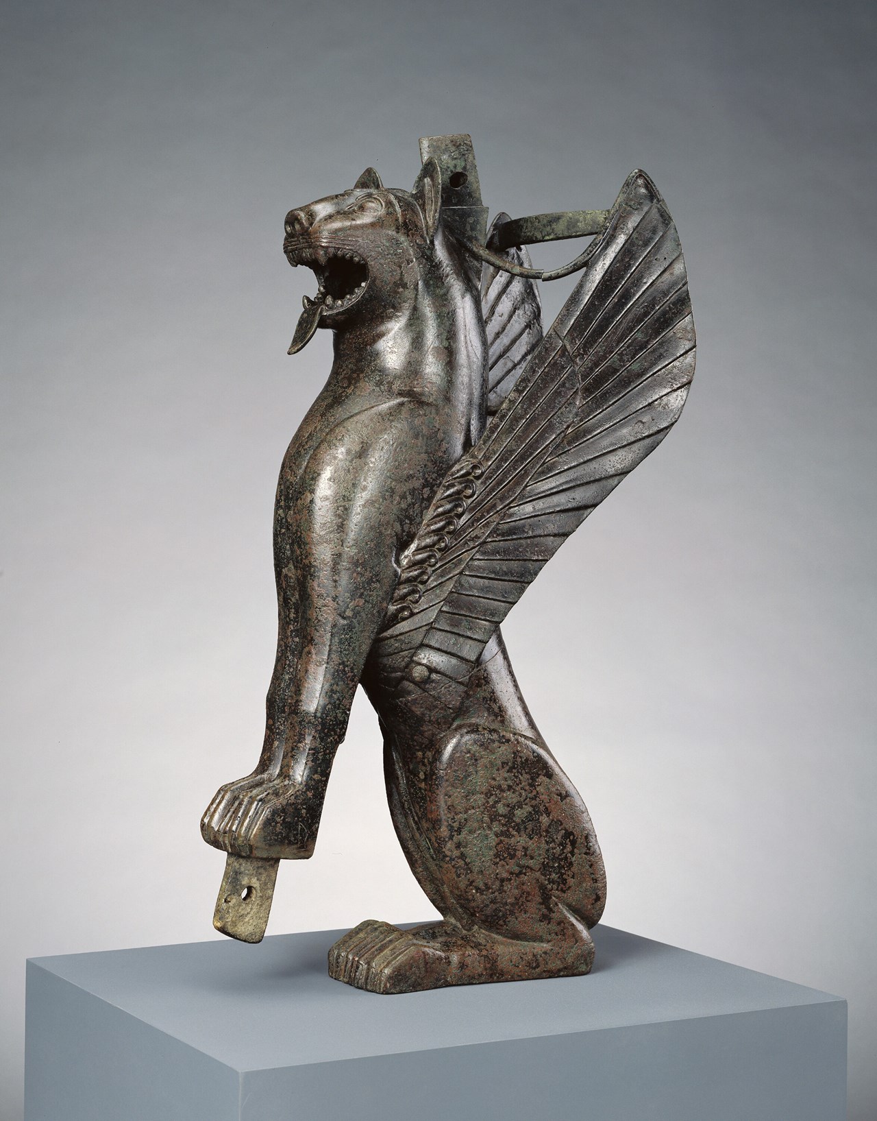 This winged feline originally served as the front leg of a wooden chair or throne. Felines were popular in the art of many Mediterranean and Near Eastern cultures. Certain stylistic features of this piece, as well as the manner in which it was made from separate pieces of bronze joined together, suggest that this work was created in Spain, specifically in the kingdom of Tartessos. The form of the feline's brow is a Tartessian characteristic, as is the triangle design in the creature's ear. https://www.getty.edu/art/collection/object/103TQK