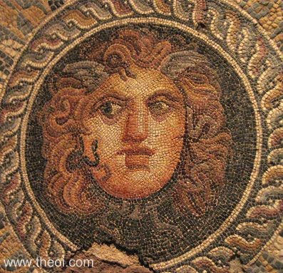 The head of Medusa ("the Gorgoneion") is depicted with wide, staring eyes, wings on the brow, red, curly hair, two black vipers coiling at the cheek, and a pair of snake-tails knotted below the chin.
