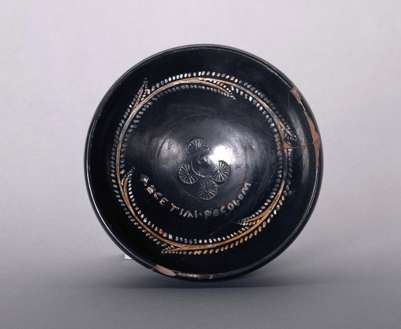 Black-glazed pottery poculum (drinking-cup) with painted and stamped decoration, and a painted inscription reads "AECETIAI POCOLOM" or 'Aecetia's cup'. https://www.britishmuseum.org/collection/object/G_1847-0806-41?selectedImageId=464233001